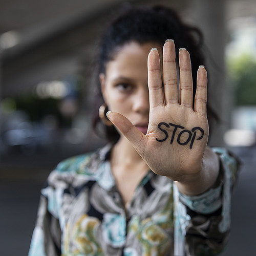 Una giovane donna tende la mano. Dice STOP.